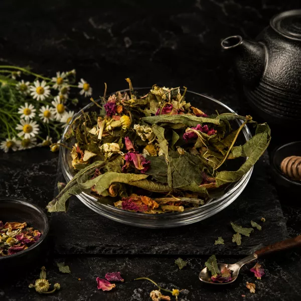 Aufgebrühte Kräutertee-Mischung in einer Tasse mit sichtbaren Rosenblüten und grünen Kräutern – aromatische Haustee-Mischung von Charaf Gewürze Berlin