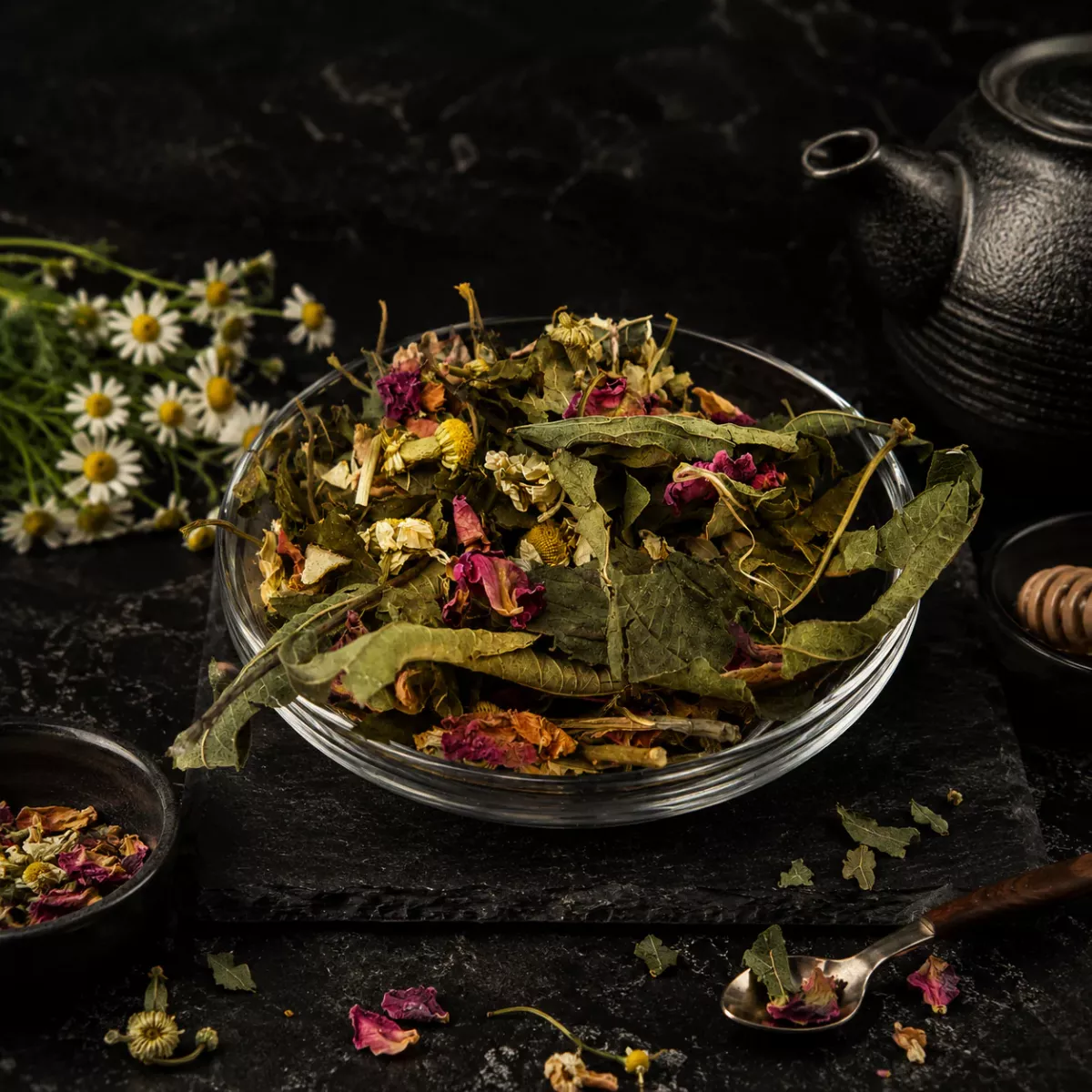 Aufgebrühte Kräutertee-Mischung in einer Tasse mit sichtbaren Rosenblüten und grünen Kräutern – aromatische Haustee-Mischung von Charaf Gewürze Berlin